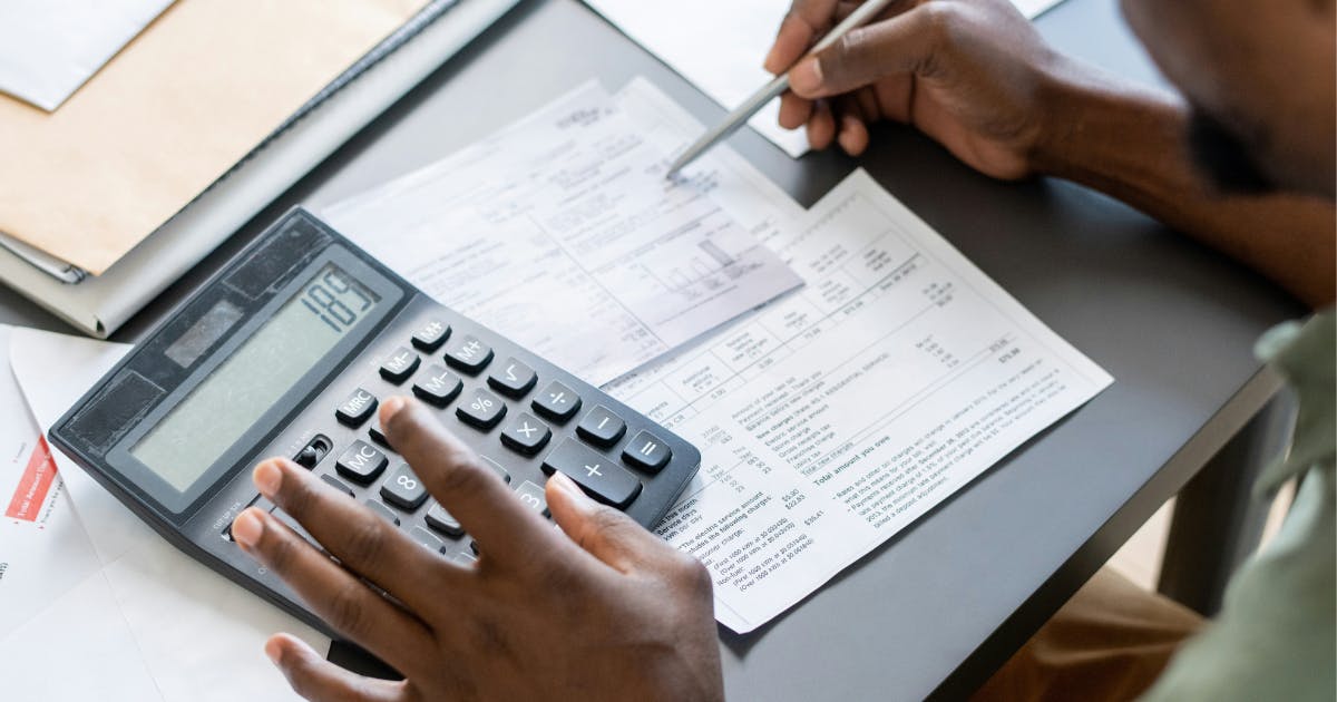 Close-up of hands managing accounts payable payment process with invoice and calculator.
