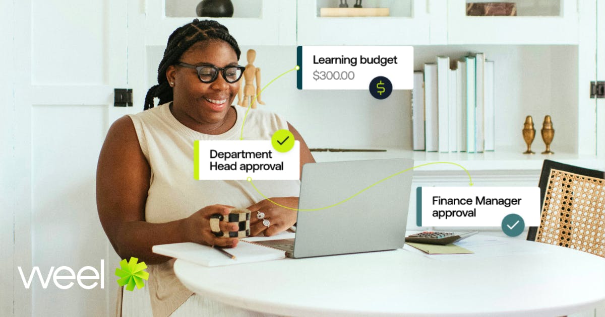 An employee smiling at their laptop while reviewing Weel's wellbeing budget processes, showcasing how spend management solutions can simplify expense tracking and promote employee wellbeing.