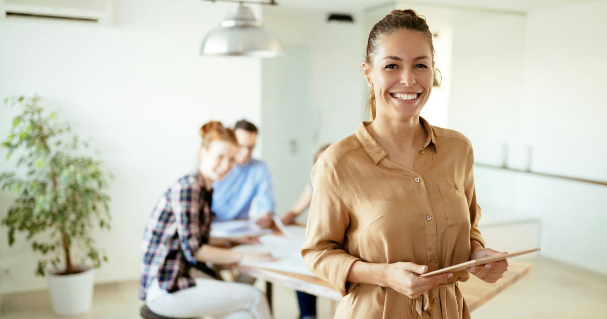 A happy employee smiling while using an iPad, demonstrating how technology enhancements can contribute to employee satisfaction and engagement.