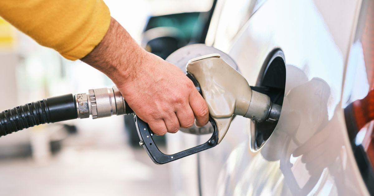 A hand holding a fuel pump, fueling up a car, representing the practicality of business fuel cards in Australia.
