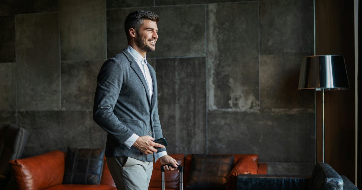 Corporate traveller in an airport lounge with a suitcase, illustrating effective ways to reduce travel costs in a business.