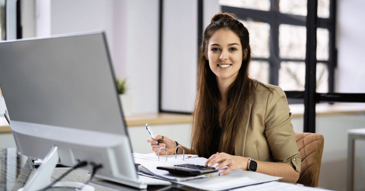 Accountant smiling in office, representing the ease of outsource accounts payable solutions